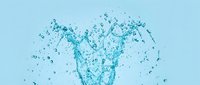 Dynamic water splash with droplets and bubbles creating crown-like formation against clean blue background for refreshing beverage and hydration concepts.