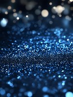 Magical blue glitter sparkles on dark background with bokeh effect and blurred lights creating dreamy atmospheric mood for festive designs.
