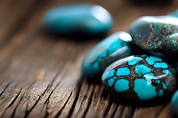 Polished turquoise stones with natural matrix patterns displayed on rustic wooden surface, showcasing vibrant blue-green color and distinctive brown veining in macro view.