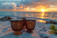 African djembe drums on sandy beach at golden sunset with ocean waves and dramatic sky, creating peaceful tropical atmosphere for meditation and music.