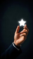 Business hand holding glowing white star symbol against dark background representing success, achievement, excellence and quality rating concept.