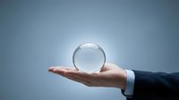 Businessman in formal attire holding transparent crystal sphere against blue sky background, symbolizing vision, future planning, and business strategy concepts.