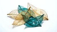 Transparent glass leaves in golden yellow and teal blue colors with detailed vein patterns isolated on white background for modern decor projects.