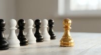 Golden chess pawn standing out from crowd of black and white pawns on wooden board, leadership and uniqueness concept for business strategy.