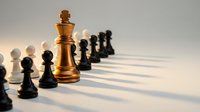 Golden chess king piece standing prominently among black and white pawns on board with dramatic lighting and shadows for strategic business concepts.