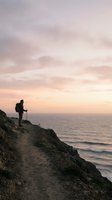 Hiker with backpack standing on coastal cliff at sunset overlooking ocean waves and horizon, adventure travel and outdoor exploration concept for lifestyle and wellness.