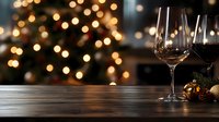 Wine glasses on rustic wooden table with blurred Christmas tree lights and decorations creating magical holiday atmosphere, copy space for festive design.