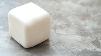 White cube soap bar on textured concrete surface for natural skincare and hygiene products.