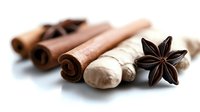 Aromatic spices arrangement with cinnamon sticks, star anise, and ginger root on white background for culinary and food design use.