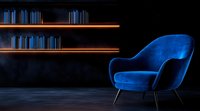 Modern blue velvet armchair against dark background with illuminated wooden shelves creating minimalist interior atmosphere for luxury home decor and furniture design.