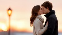 Young couple sharing romantic kiss at sunset with warm golden light and street lamp creating intimate atmosphere for love and relationship concepts.