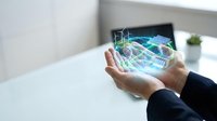Businessman holding transparent tablet displaying holographic shopping cart and digital retail interface for e-commerce and online shopping applications.