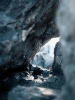 Weathered rock formation with natural opening framing distant snowy landscape, suitable for nature backgrounds and editorial use.