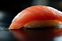 Fresh tuna nigiri sushi with glistening red fish over seasoned rice on dark surface. Premium Japanese cuisine for restaurant menus and culinary content.