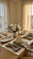 Elegant dining table setting with white flowers and natural linen napkins in warm sunlit room with beige curtains for home decor and lifestyle content.