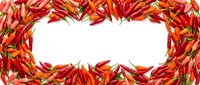 Red hot chili peppers arranged in heart shape frame on white background. Spicy vegetable border for cooking, recipe design and culinary projects.