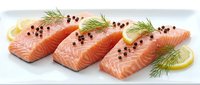 Fresh salmon fillets with dill herbs and lemon slices on white background, raw fish portions seasoned with black pepper ready for cooking and culinary preparation.