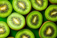 Fresh juicy kiwi fruit slices arranged in rows showing bright green flesh and black seeds on green background, macro food photography for healthy eating concept.