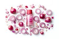 Fresh red onion rings and whole bulbs arranged around pink glass bottle on white background, flat lay composition for food and cosmetic concepts.