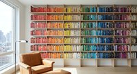 Rainbow organized bookshelf wall with color-coordinated books from red to purple creating vibrant home library interior design for reading spaces.