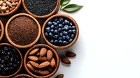 Fresh organic superfoods in clay bowls on white background - almonds, blueberries, black currants and chia seeds. Healthy eating concept for food design.