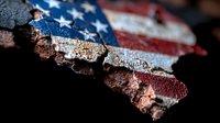 Weathered American flag paint peeling off rustic metal surface showing distressed patriotic texture with red, white and blue colors in macro close-up detail.