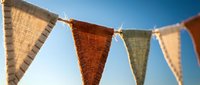 Colorful fabric bunting flags hanging on rope against clear blue sky background for outdoor party celebration and festive decoration events.