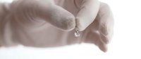 Hands holding water droplet, close-up of liquid drop suspended between fingers, macro shot for environmental, science, or wellness concepts.