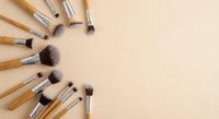 Professional makeup brushes with bamboo handles arranged in circular pattern on beige background for beauty and cosmetics applications.