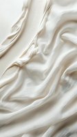 Smooth flowing white cream texture with gentle waves and soft folds creates elegant abstract background for luxury cosmetic and skincare advertising.