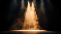 Dramatic golden spotlights beam through atmospheric haze creating ethereal rays on dark stage, illuminating empty performance space with mystical theatrical lighting.
