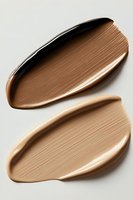 Smooth textured foundation cream swatches in dark and light brown shades on white background, showing cosmetic product texture and consistency for makeup application.