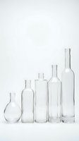 Empty clear glass bottles of various shapes and sizes arranged in row on white background for packaging design and craft projects.
