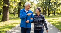Senior Caucasian man and African American woman jogging together in sunny park, enjoying healthy active lifestyle and fitness routine outdoors.