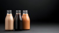 Three glass milk bottles with different flavored beverages including chocolate and strawberry drinks arranged on dark background for product photography.