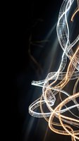 Abstract light trails creating flowing ribbons of white and golden illumination against dark background for creative digital art projects.