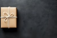 Minimalist kraft paper wrapped gift box with white twine bow on dark background with copy space. For holiday and celebration designs.