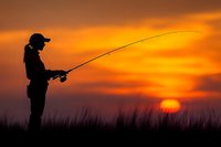 Silhouette of angler fishing at sunset with dramatic orange sky and golden hour lighting creating peaceful outdoor recreation scene.