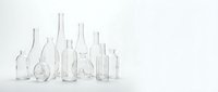 Collection of empty clear glass bottles and vases in various shapes and sizes arranged on white background for minimalist home decor and design projects.