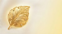 Golden ornate leaf with intricate filigree patterns on cream background for luxury design projects and elegant decorative applications.