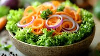 Fresh mixed salad with curly lettuce leaves and spiral carrot ribbons in rustic bowl, healthy vegetarian meal preparation for clean eating and nutrition.