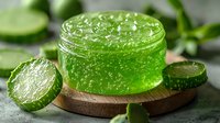 Fresh cucumber gel with aloe vera in glass jar on wooden board, surrounded by sliced cucumbers. Natural skincare and beauty product for spa treatments.