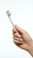Closeup of a woman's hand holding a beige toothbrush against white background, isolated for dental hygiene, oral care product marketing and healthcare design use.