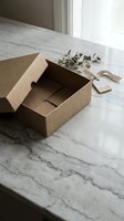 Open brown cardboard shipping box on marble surface with natural lighting for e-commerce packaging and delivery concepts.