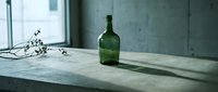 Empty green wine bottle and dried flowers on concrete windowsill with industrial interior backdrop, suitable for minimalist design, lifestyle, and editorial projects.