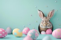 Adorable brown bunny with decorated Easter eggs in pastel colors on mint background. Festive spring holiday composition with rabbit and polka dot pattern eggs.