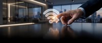 Hand touching glowing wifi symbol on modern office desk with city skyline background, representing wireless connectivity and digital communication technology.