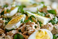 Fresh tuna salad with hard boiled eggs, mixed greens and herbs. Healthy protein-rich meal for lunch or dinner preparation in modern kitchen.