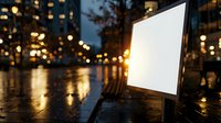 Empty white billboard at night with wet reflective pavement, city lights and buildings in background creating atmospheric urban scene with bokeh effect.