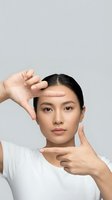 Young Asian woman making frame gesture with hands around face on neutral background for beauty and skincare concepts.